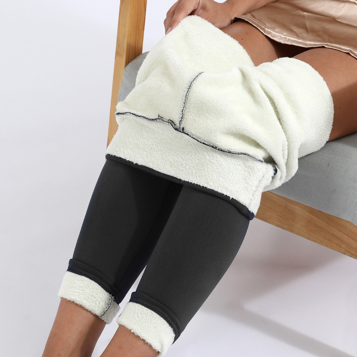 Black fleece-lined leggings with a plush white interior being put on, showing smooth outer material.