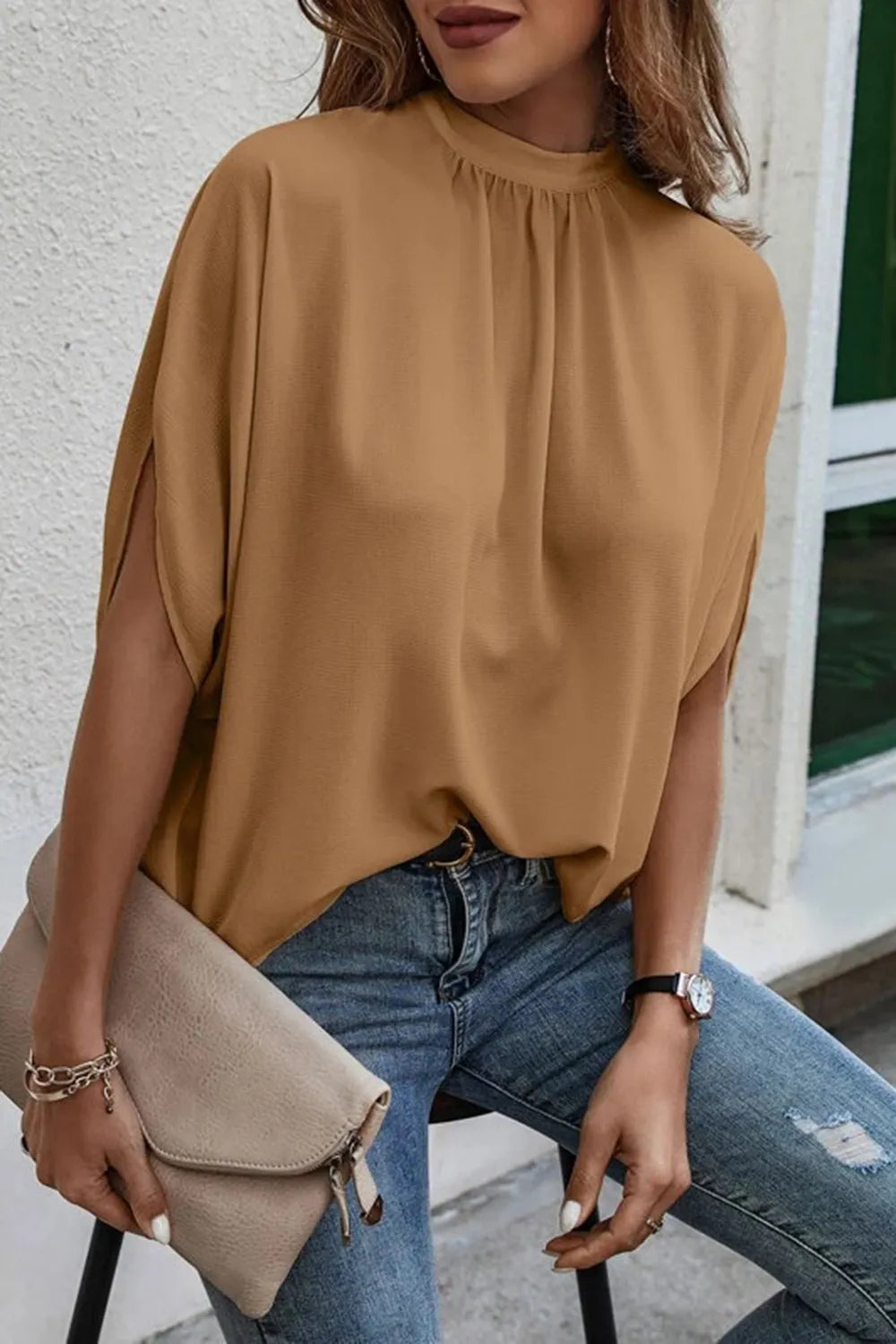 Light-colored Plush Fashion Hub blouse with tie-back, half-sleeves, and side slit, showcasing a stylish, feminine top design.