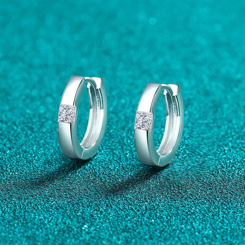 Sterling silver moissanite huggie earrings with sparkling gemstones, crafted for a stylish and elegant look.