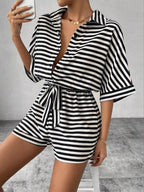 Striped button-up belted romper jumpsuit by Trendsi, featuring a stylish design with a collar, long sleeves, and a waist belt.