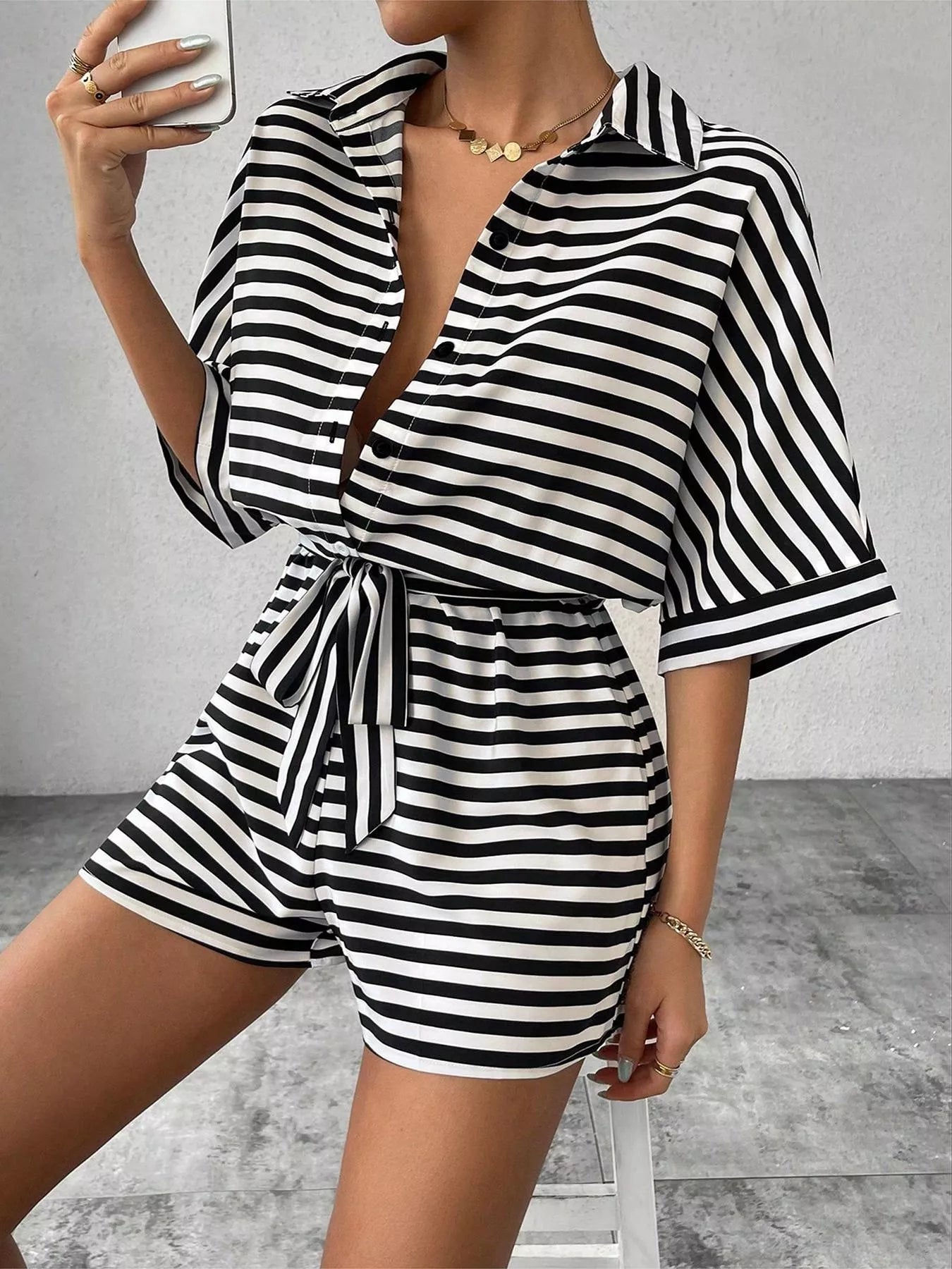 Striped button-up belted romper jumpsuit by Trendsi, featuring a stylish design with a collar, long sleeves, and a waist belt.