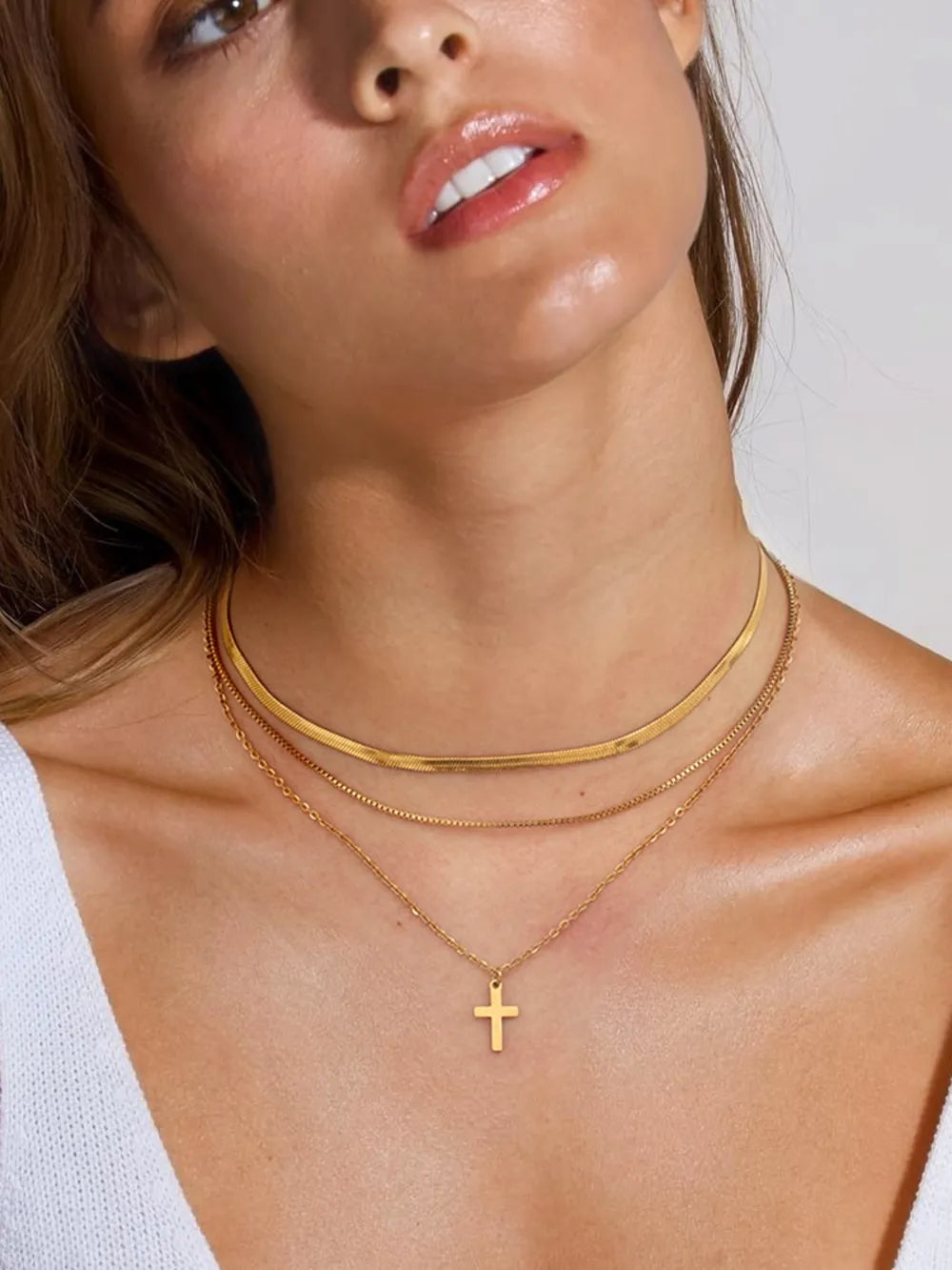 18K gold-plated three-layered cross necklace with delicate chains and detailed cross pendants, displayed on a neutral background.