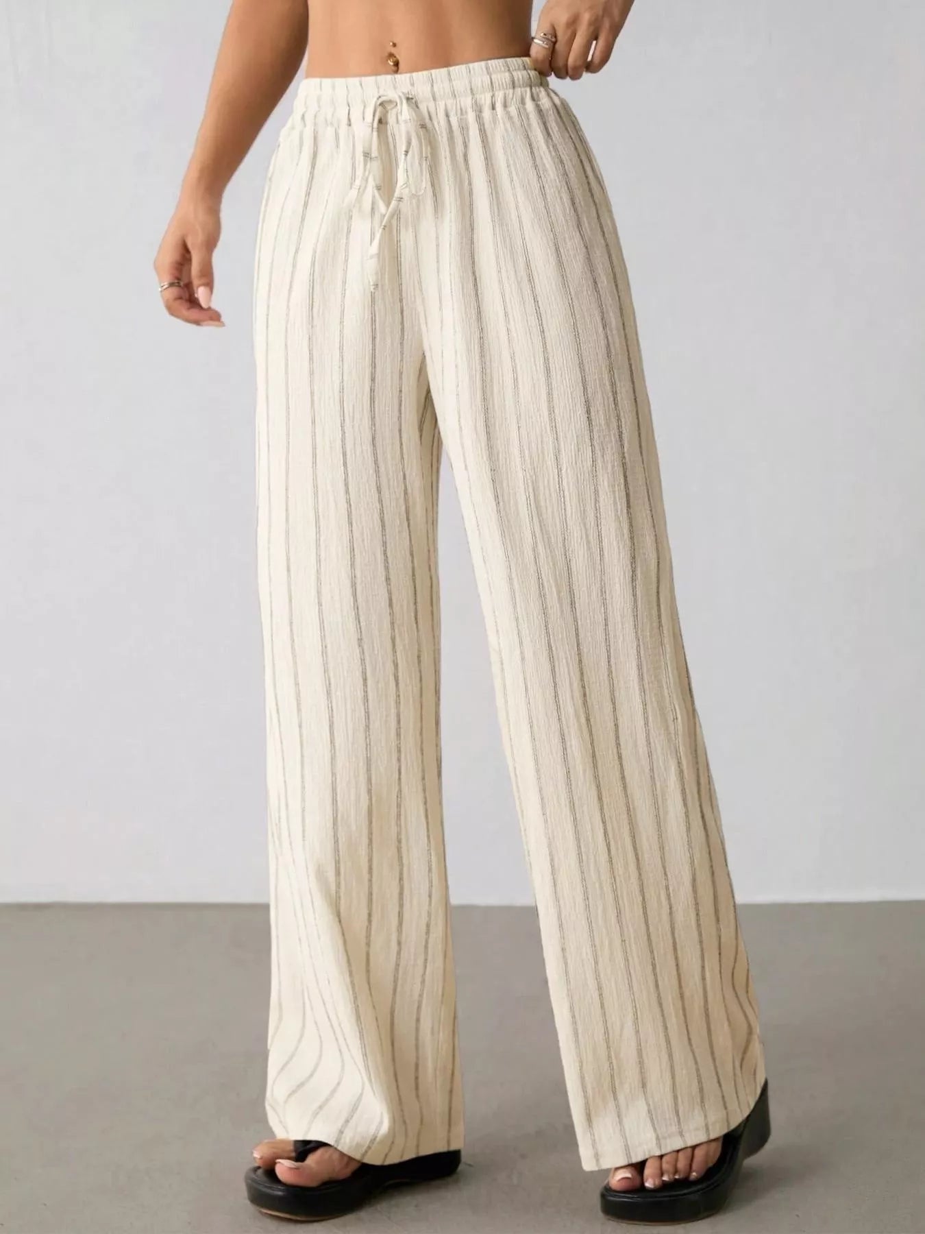 Striped wide-leg drawstring pants from Trendsi, featuring comfortable fit and stylish design with vertical stripe pattern.