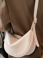 Minimalist crescent-shaped crossbody bag in smooth PU leather, trendy shoulder purse for casual and chic outfits.