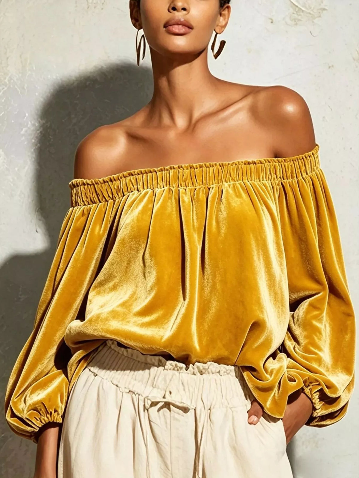 Black off-shoulder velvet long sleeve T-shirt from Trendsi with a fitted design and soft fabric, shown on a white background.