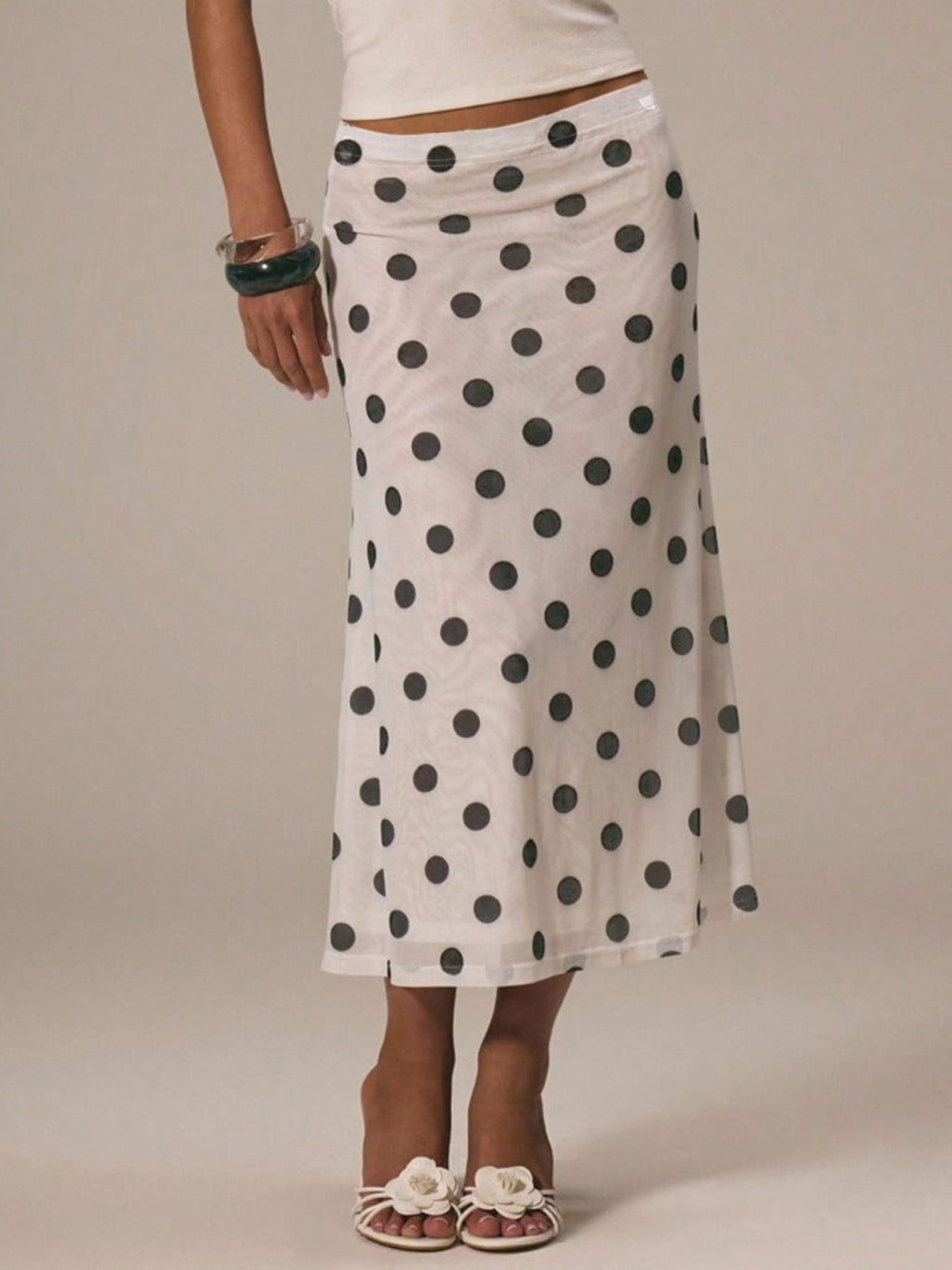 Women's vintage-inspired polka dot midi skirt by Trendsi, high-waisted A-line design, flowing fabric in classic black and white dots.