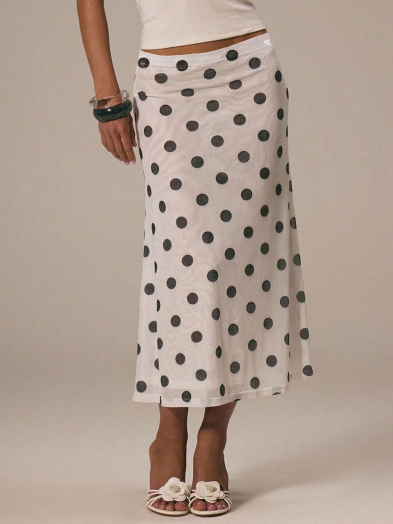 Women's vintage-inspired polka dot midi skirt by Trendsi, high-waisted A-line design, flowing fabric in classic black and white dots.