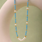 Turquoise pearl beaded necklace from Shopimist featuring a string of vibrant turquoise and white pearls on a delicate chain.