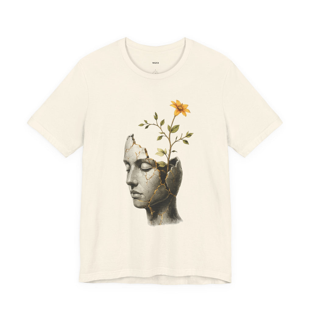 Wear Your Worship SEEN Still Becoming T-Shirt featuring cracked sculpture and blooming flower design on soft fabric.