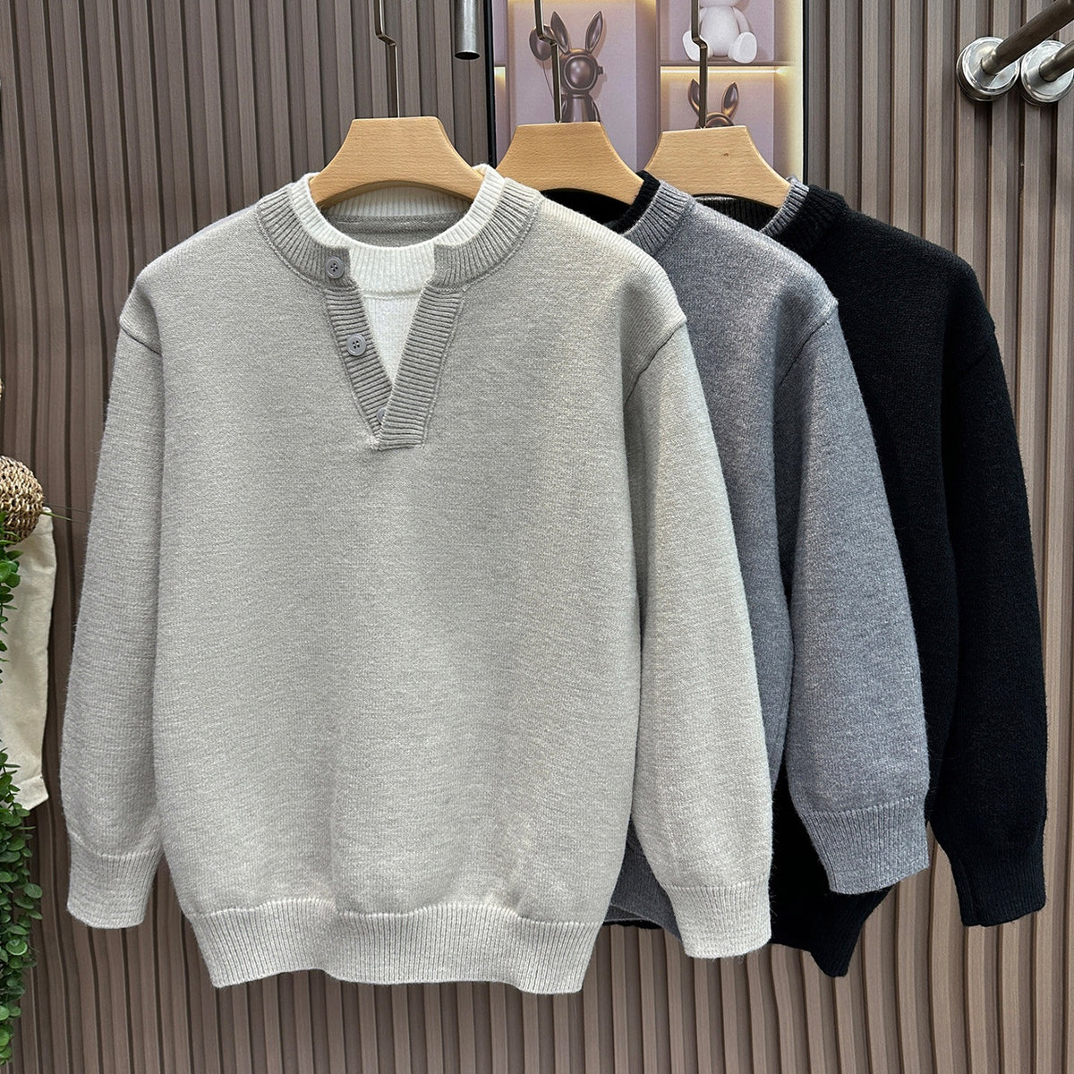 Light gray knit sweater with button-placket, layered white collar, ribbed cuffs and hem, on a hanger.