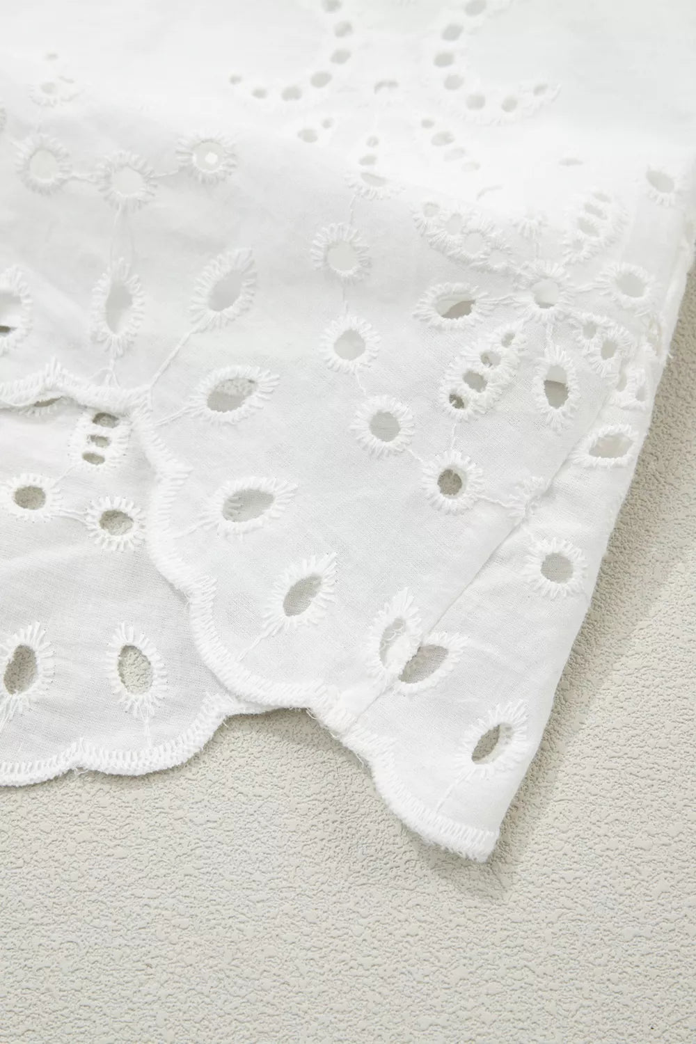 Solid color eyelet embroidered T-shirt mini dress from Trendsi, featuring short sleeves and decorative eyelet embroidery.