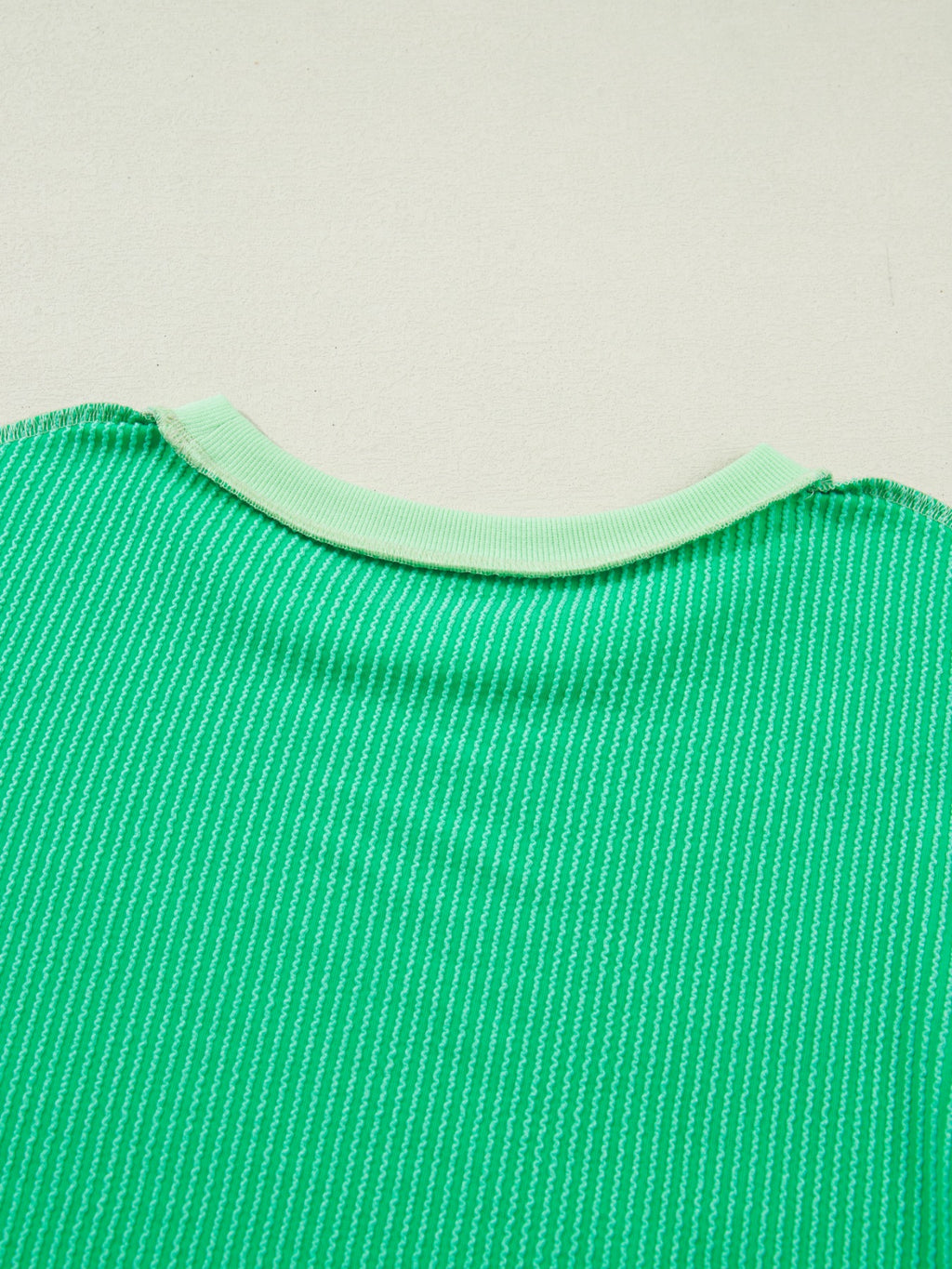 Women's ribbed twist hem short sleeve T-shirt with contrast stitching, featuring a fitted style and subtle ribbed texture.