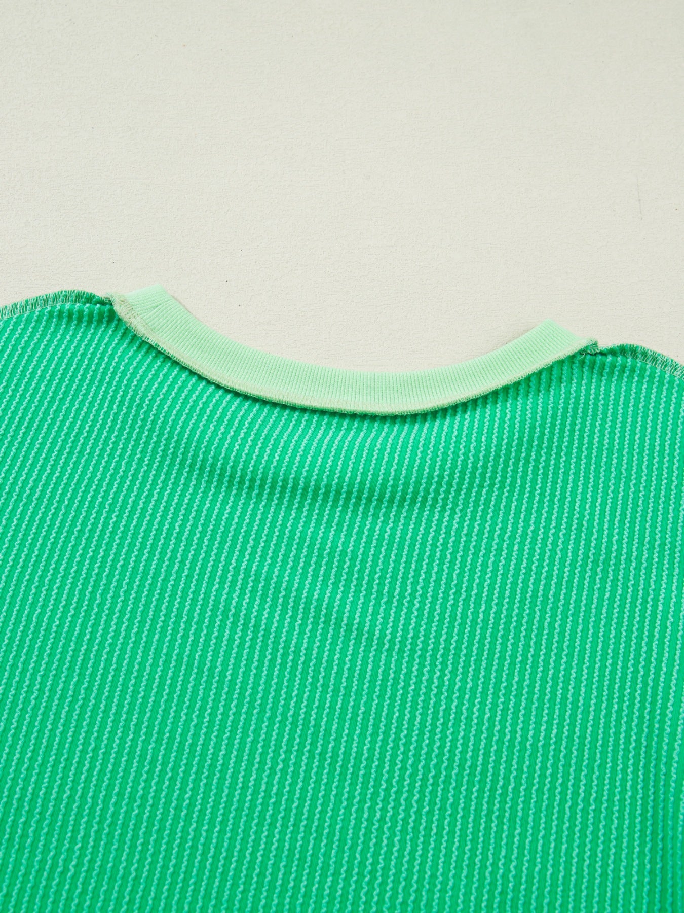 Women's ribbed twist hem short sleeve T-shirt with contrast stitching, featuring a fitted style and subtle ribbed texture.