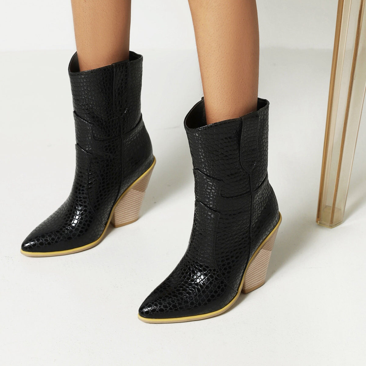 Black faux-leather cowboy boots with a reptile texture, pointed toe, and wooden block heel.