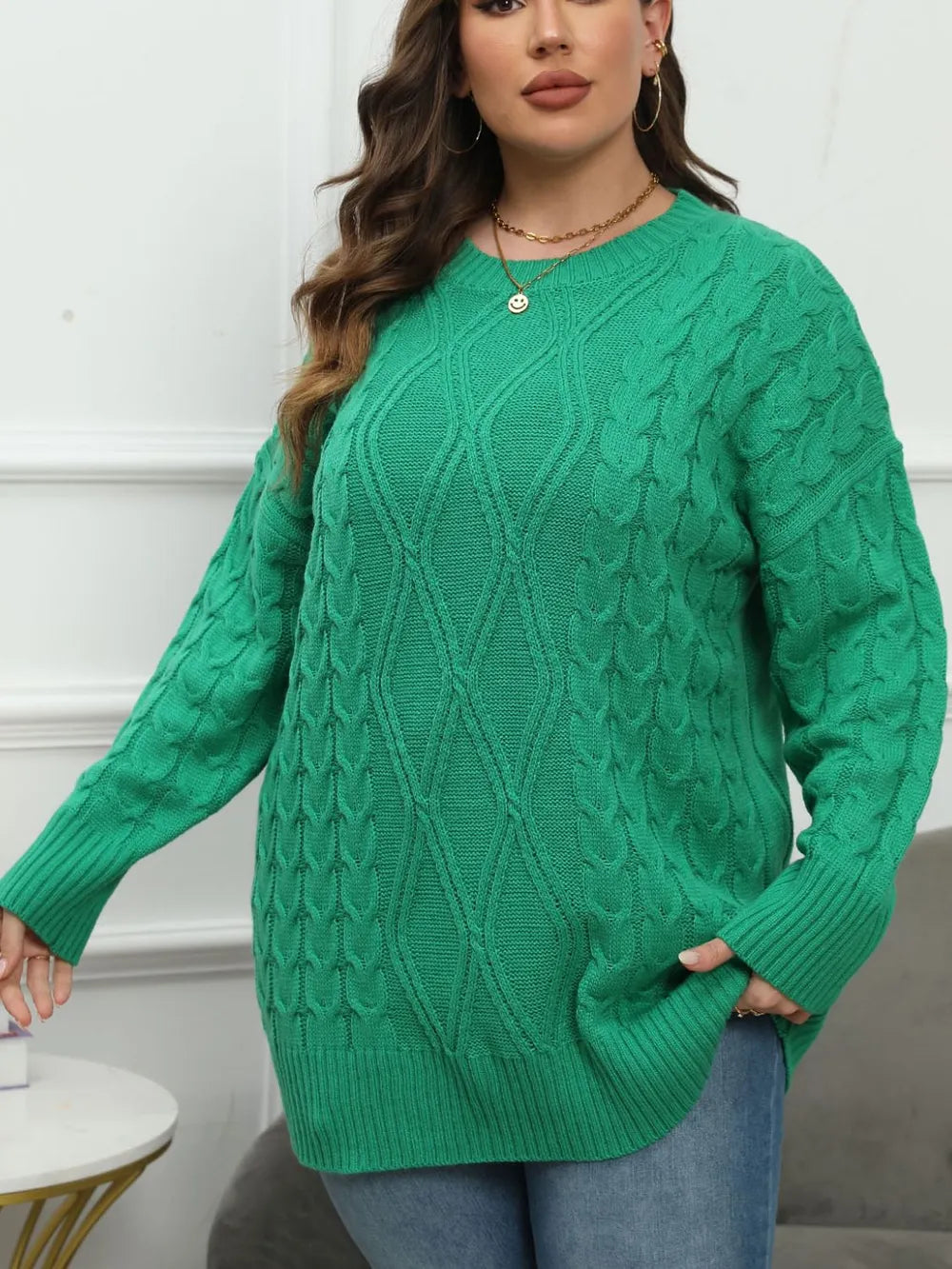 Plus-size green cable knit sweater with crew neck, long sleeves, and ribbed trim.