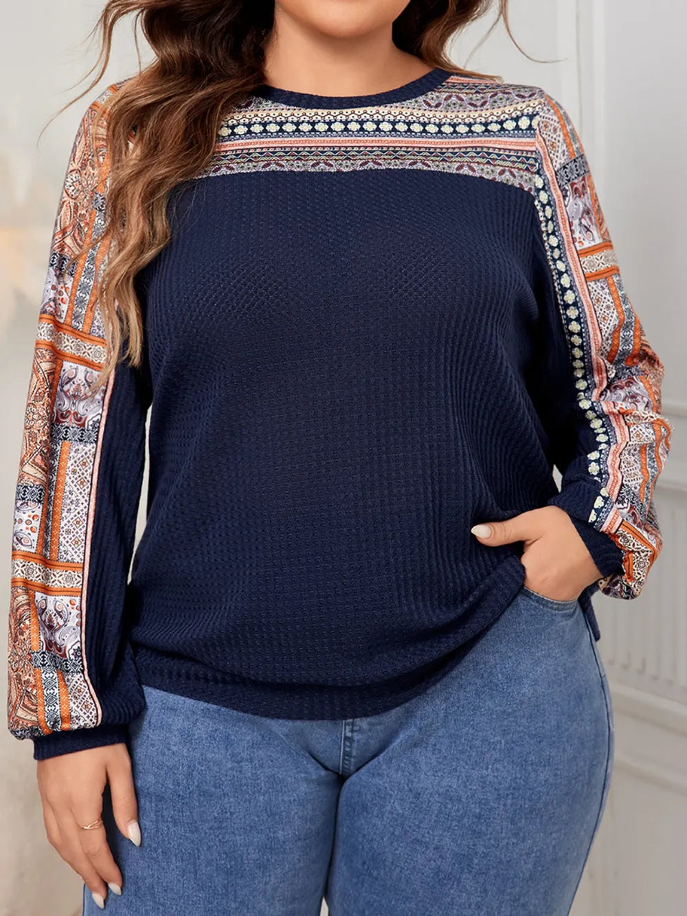 Navy blue waffle knit long-sleeve top with multicolored patterned panels on shoulders, sleeves, and chest yoke.