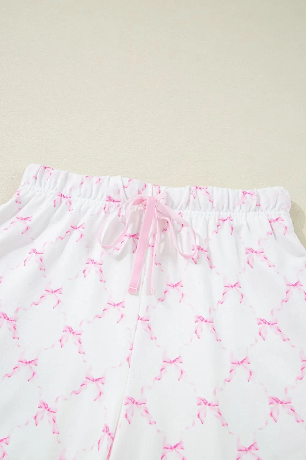 Simply Love bow print lettuce trim round neck top and shorts lounge set, featuring a comfortable, casual design with bow accents.