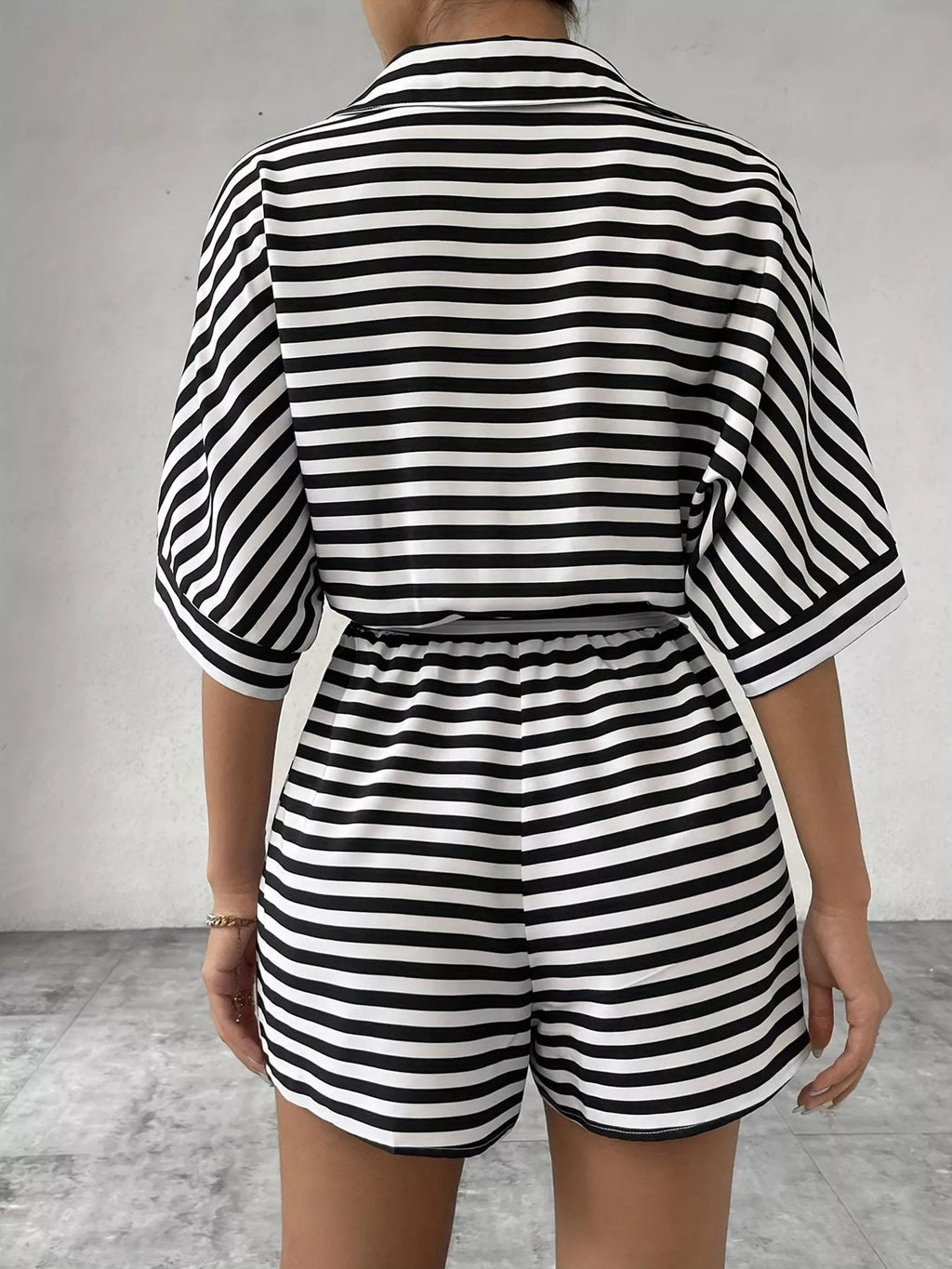 Striped button-up belted romper jumpsuit by Trendsi, featuring a stylish design with a collar, waist belt, and short sleeves.