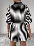 Striped button-up belted romper jumpsuit by Trendsi, featuring a stylish design with a collar, waist belt, and short sleeves.