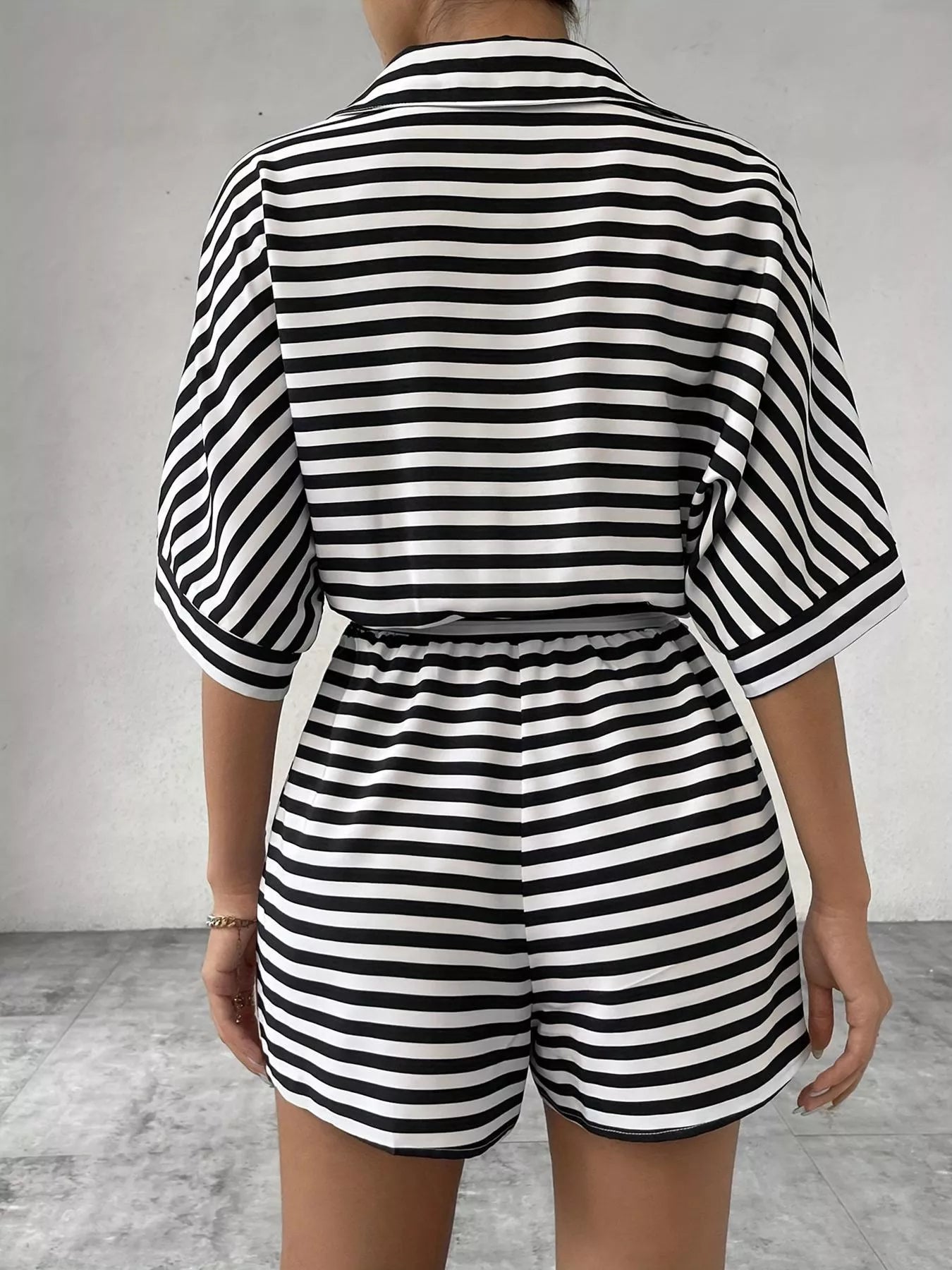 Striped button-up belted romper jumpsuit by Trendsi, featuring a stylish design with a collar, waist belt, and short sleeves.