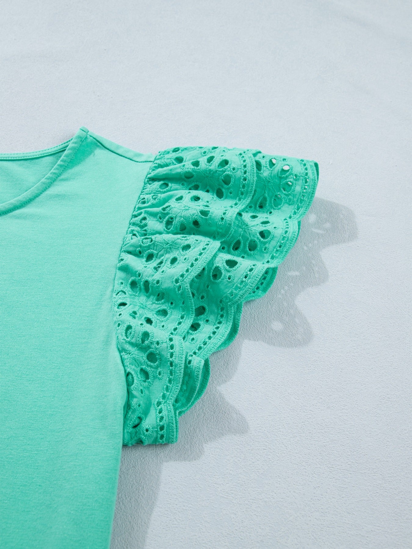 Ruffled eyelet lace cap sleeve top with cutout detail, trendy women's blouse by Trendsi featuring feminine design and lightweight fabric.