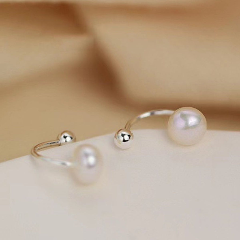 Sterling silver pearl stud earrings with round white pearls, crafted by Shopimist, on a plain background.