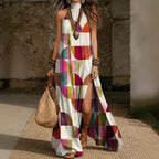 Women's printed halterneck split maxi dress by Plush Fashion Hub, sleeveless, loose fit with vibrant floral pattern.