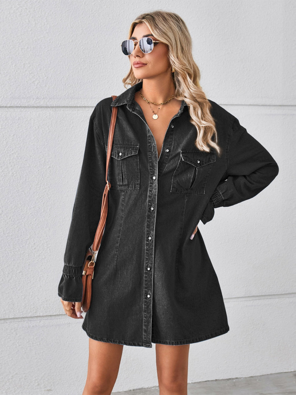 VYSN pocketed dropped shoulder mini denim dress hanging on a hanger showcasing its relaxed fit and stylish design.