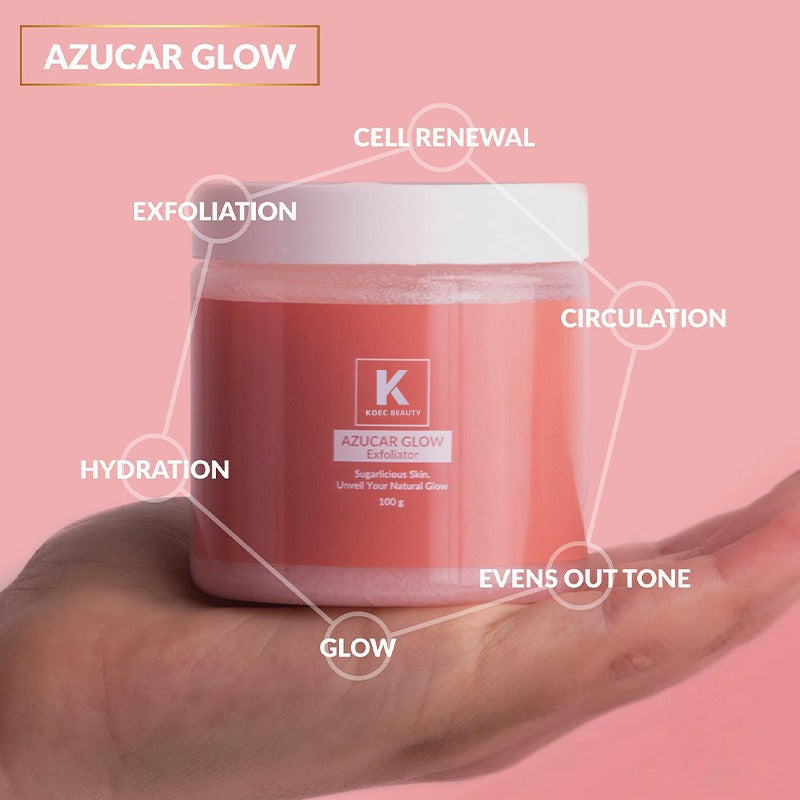 A hand holds a pink plastic jar of Azucar Glow Exfoliator with a white lid.