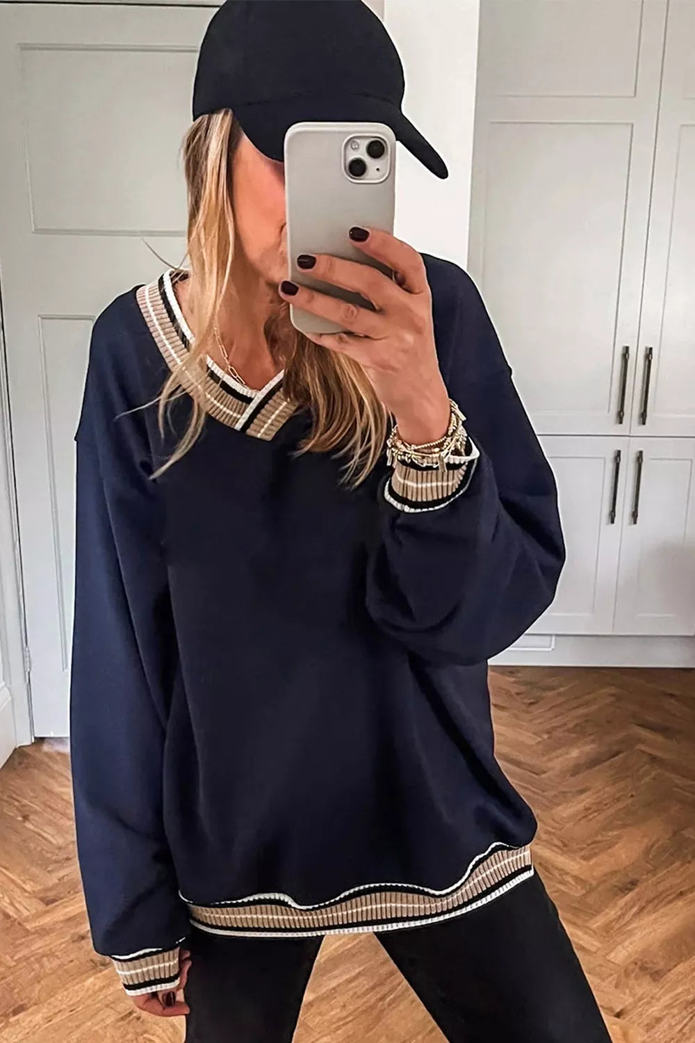 Contrast striped trim V-neck sweatshirt from Trendsi, featuring a cozy fit with stylish striped accents on the neckline.
