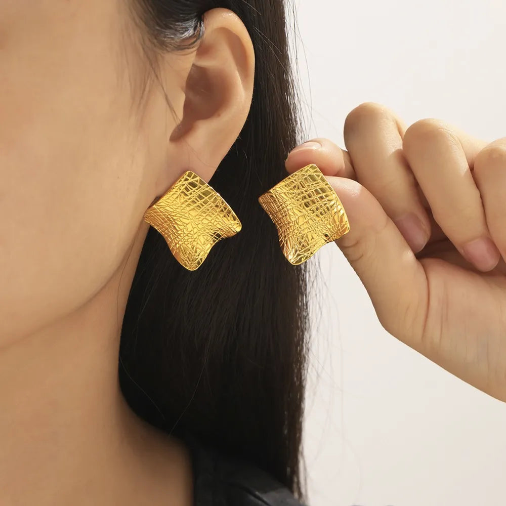 Textured titanium steel stud earrings from Plush Fashion Hub, close-up view showing their sleek, modern design and shiny finish.