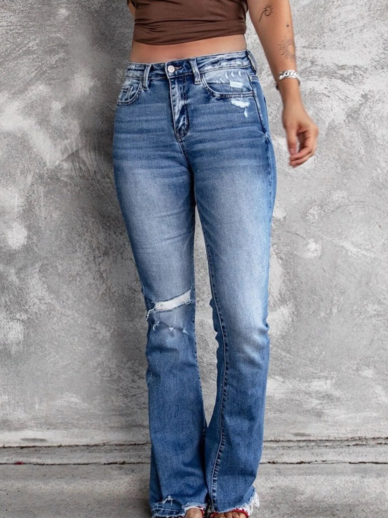 Distressed flare denim jeans by Plush Fashion Shop featuring ripped details and a high-waist fit, displayed on a model.