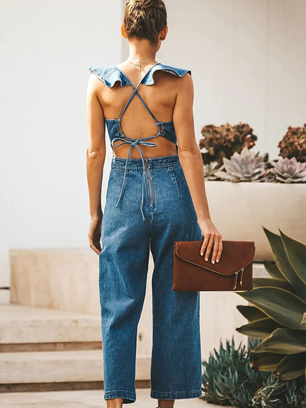 Backless sleeveless denim jumpsuit with ruffled details from Trendsi, featuring a fitted waist and casual denim jeans style.