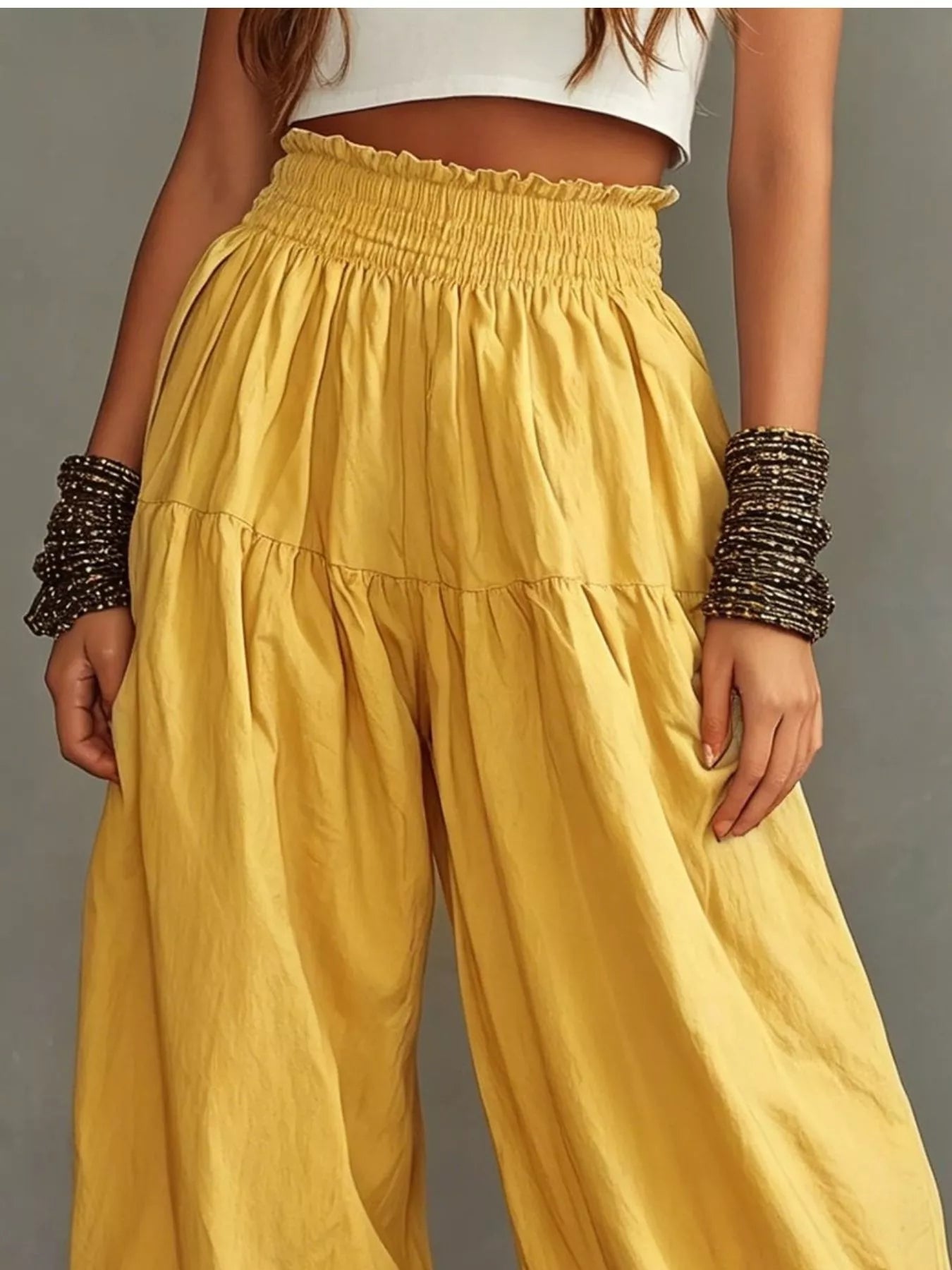 Plus size wide-leg pants with smocked waist and ruffle hem, featuring a full size fit and trendy design by Trendsi.