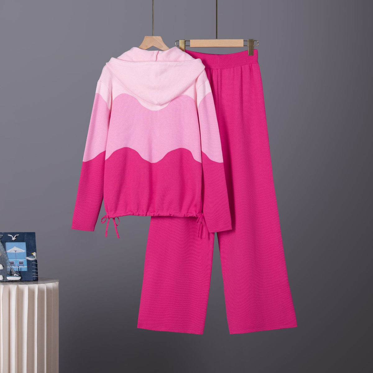 Pink knit lounge set: hooded sweater with wavy color-block pattern and drawstring hem, plus matching wide-leg pants.
