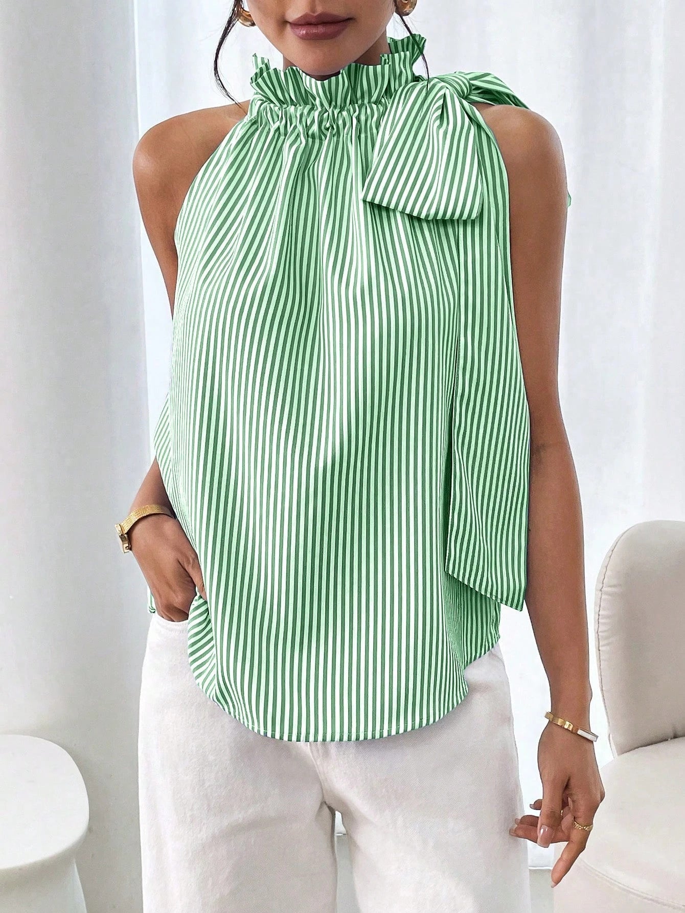 Women's striped sleeveless blouse by Plush Fashion Hub featuring ruffle high neck, lace trim, and tie-knot bow detail.