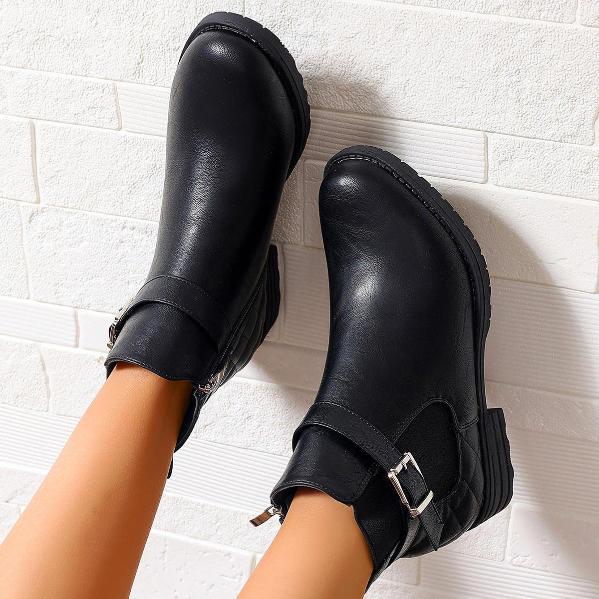 Black leather ankle boots, featuring buckled straps, side zippers, and quilted heels.