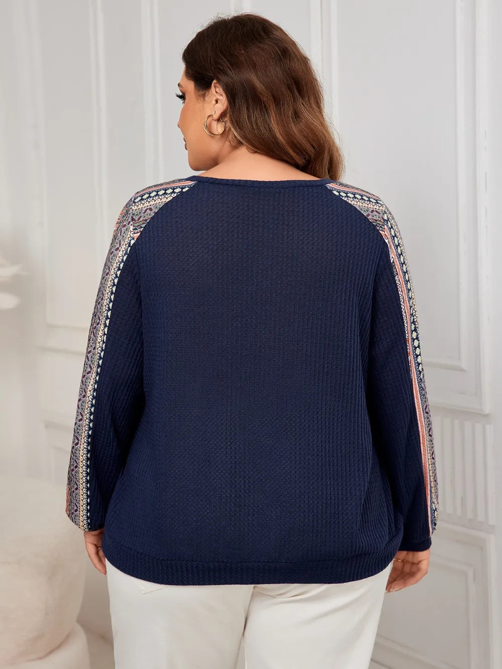 Dark blue waffle knit long-sleeve top with patterned raglan sleeves, seen from behind.