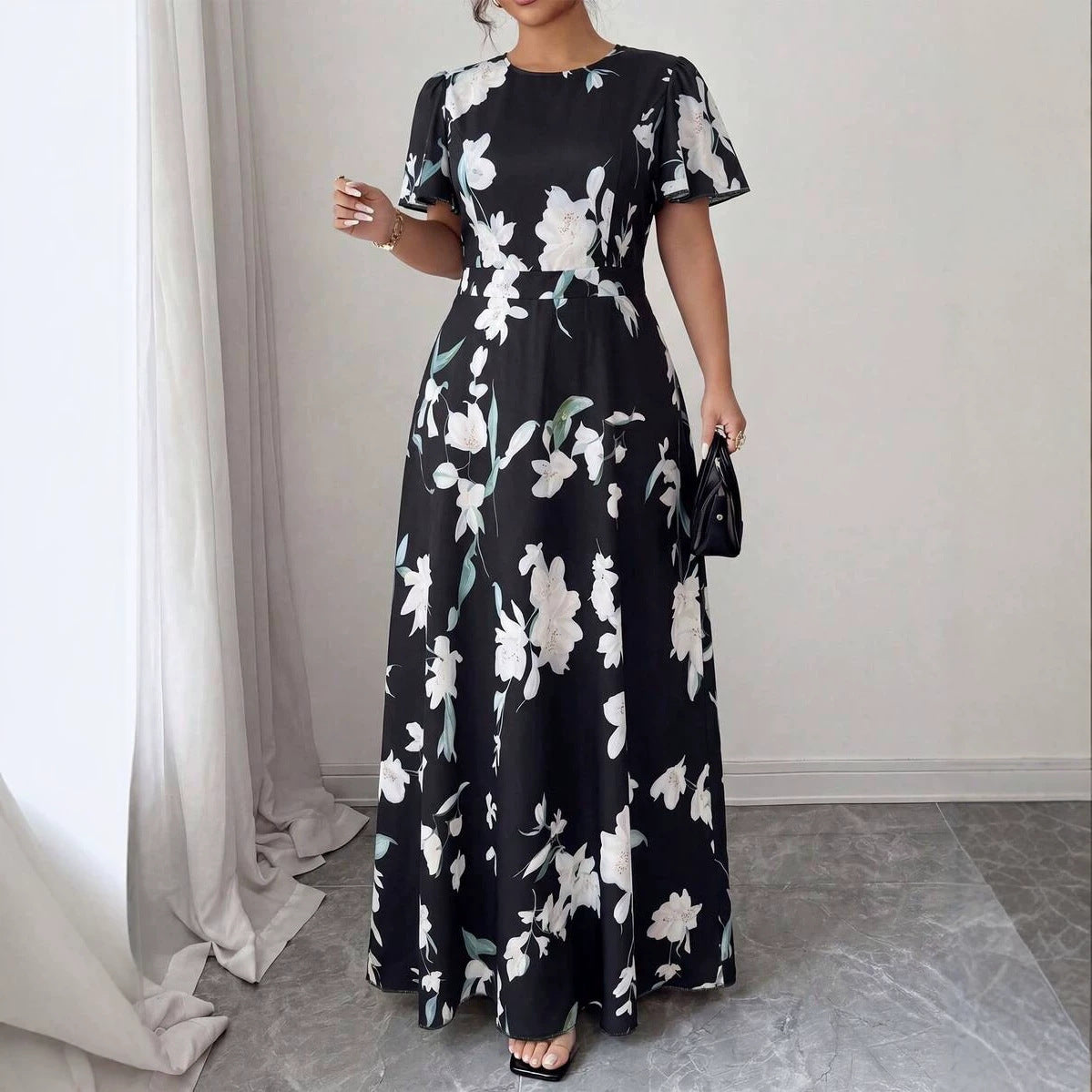 Black maxi dress with white floral pattern, round neckline, and short flutter sleeves.