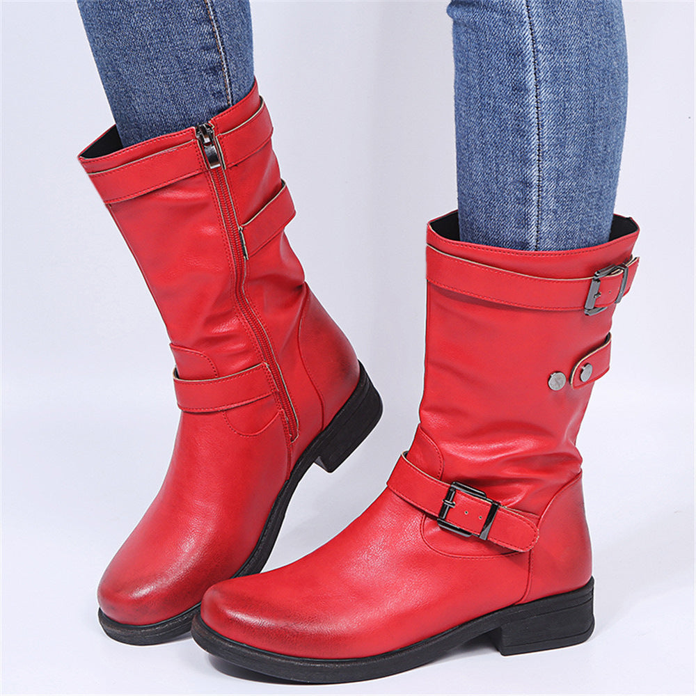 Red leather mid-calf boots with side zippers, buckled straps, and low block heels, worn with blue jeans.