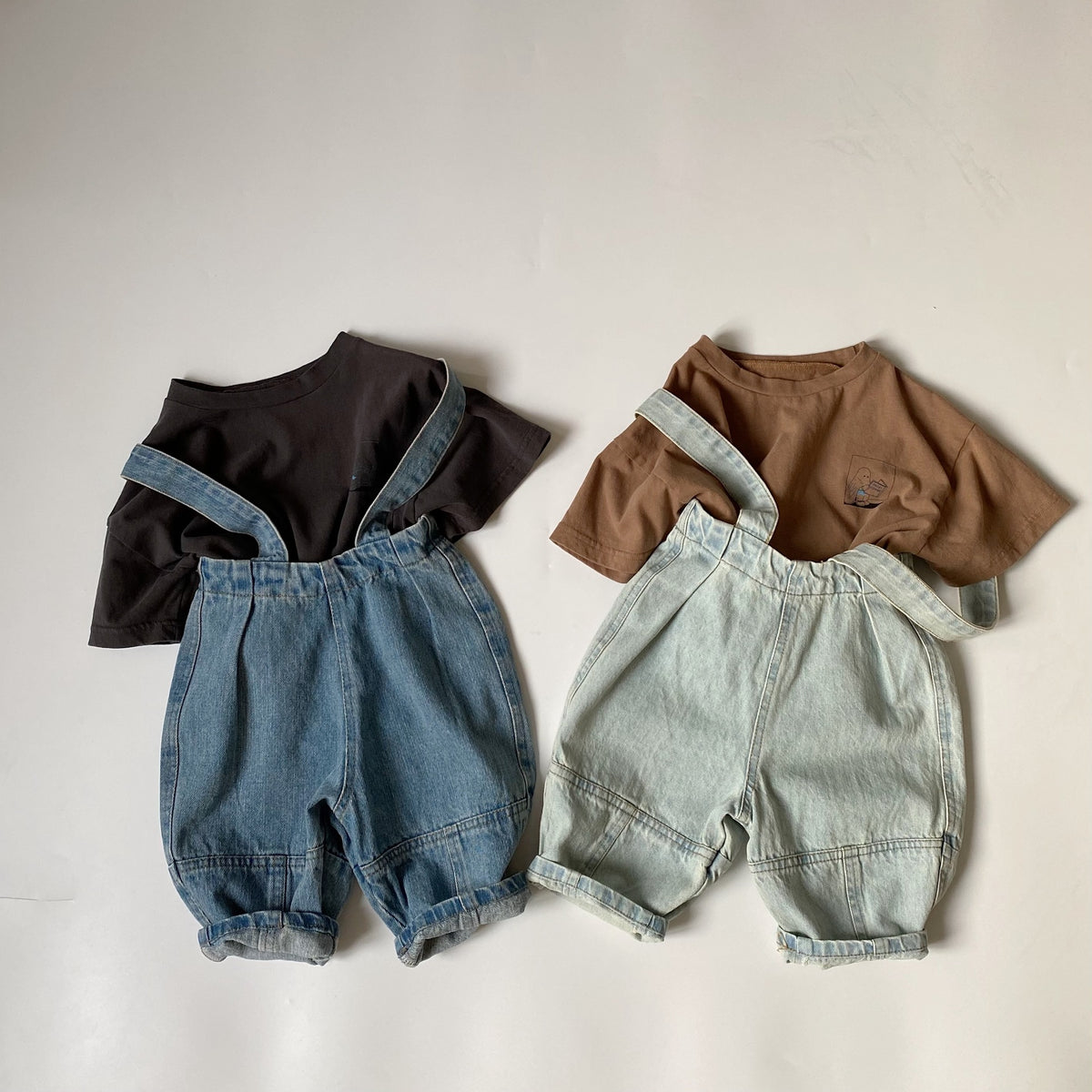 Two children's outfits with denim overalls paired with solid black and brown t-shirts.