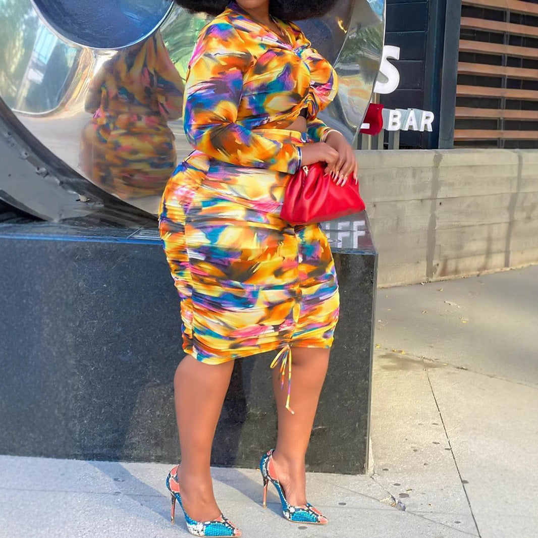 Colorful abstract-print two-piece mesh outfit with a crop top and ruching on the skirt and sleeves.