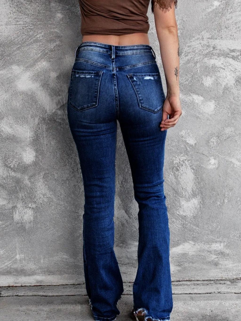 Distressed flare denim jeans by Plush Fashion Shop featuring ripped details and a high-waisted fit on model.
