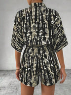Striped button-up belted romper jumpsuit by Trendsi, featuring a stylish design with a collar and waist tie, displayed on a model.