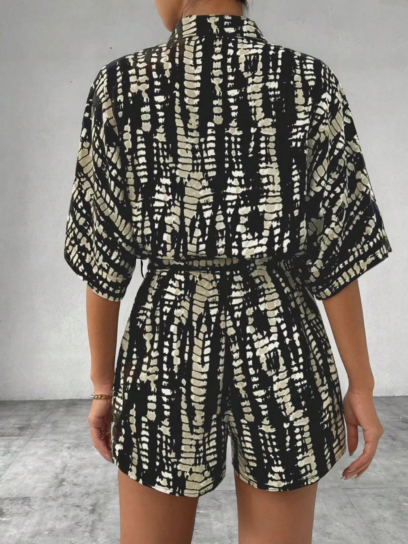 Striped button-up belted romper jumpsuit by Trendsi, featuring a stylish design with a collar and waist tie, displayed on a model.