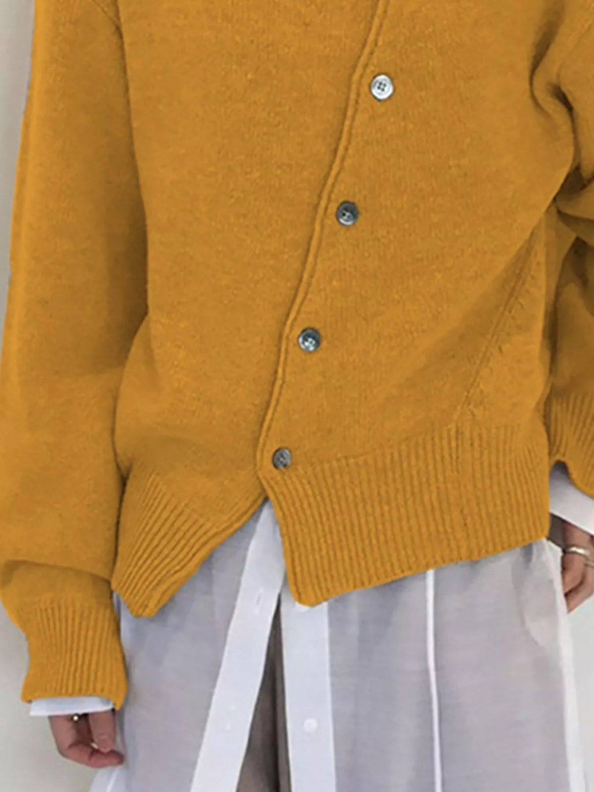 Asymmetric button-down sweater by Trendsi, featuring a stylish uneven hem and long sleeves, shown in a close-up view.
