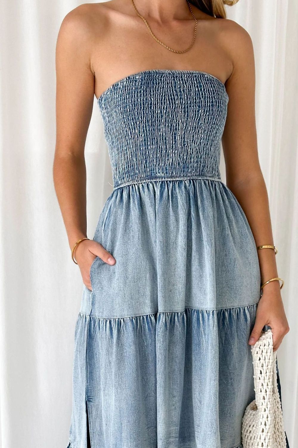VYSN smocked tube slit tiered denim dress showing a fitted bodice, tiered skirt, and slit detail on a model.
