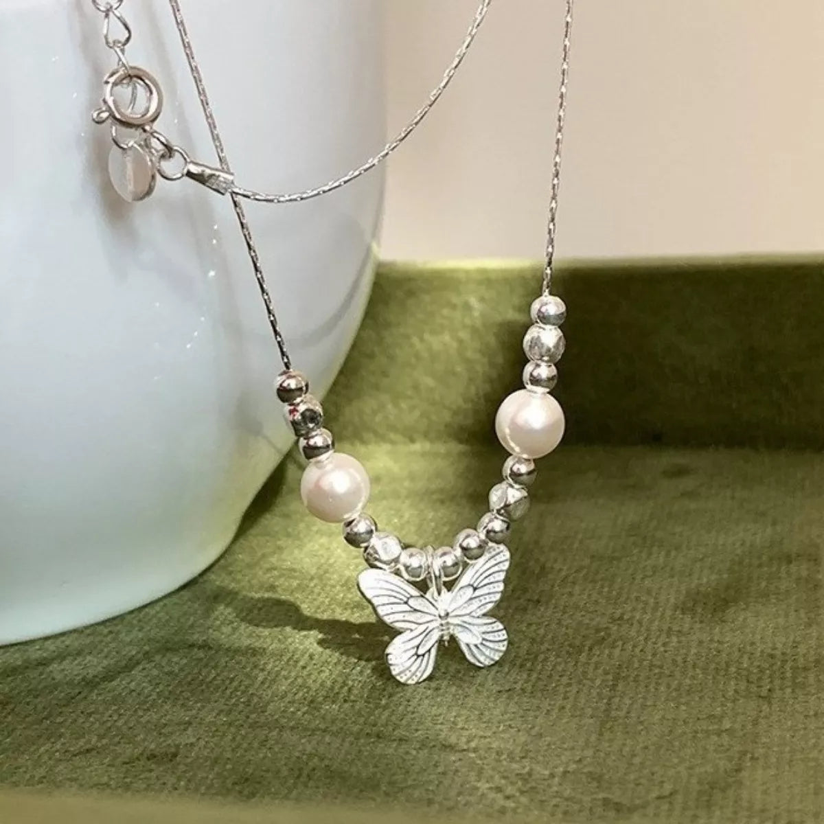 Elegant butterfly pearl pendant necklace from Plush Fashion Hub featuring a delicate pearl and butterfly charm on a silver chain.