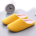 Minimalist yellow cotton indoor slippers with a soft, pink and white striped interior lining.