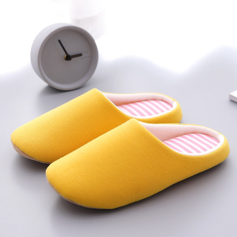 Minimalist yellow cotton indoor slippers with a soft, pink and white striped interior lining.